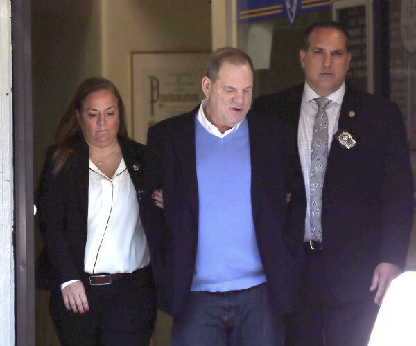 Harvey Weinstein in centered between two officers as he leaves the NYPD's 1st Precinct in handcuffs.