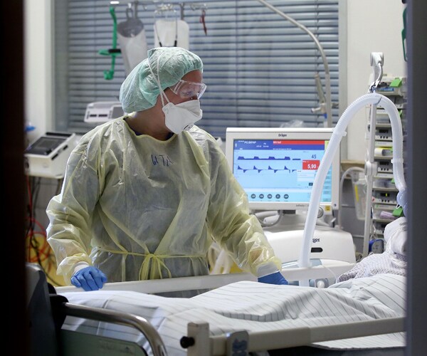 a healthcare worker attends to a covid 19 patient in germany
