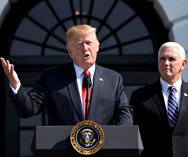 President Donald Trump speaks with Vice President Mike Pence over his left shoulder