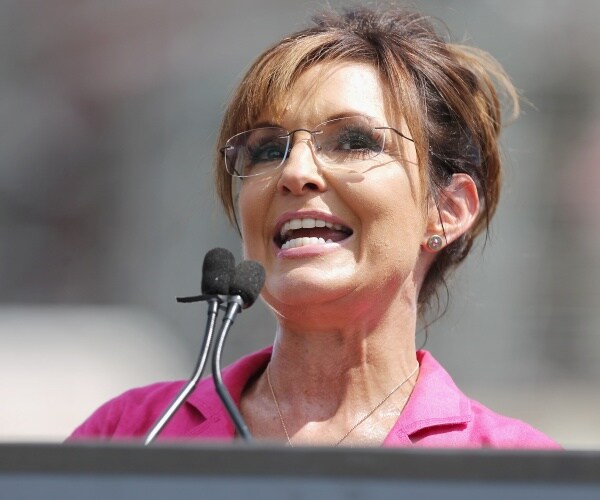palin in a pink top speaking at a podium outside