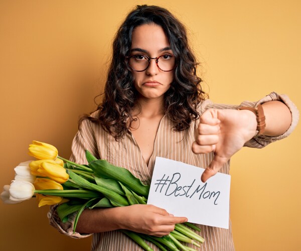 angry woman giving thumbs down and holding best mom sign and flowers