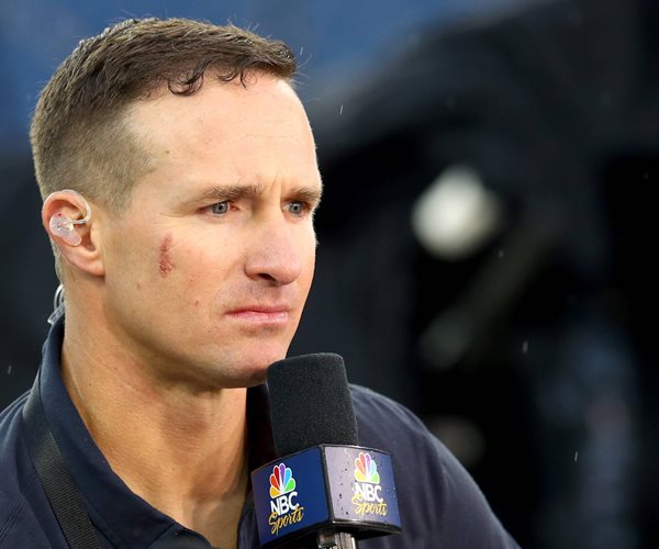 Drew Brees holds a microphone.