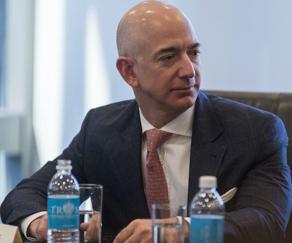 jeff bezos sits in the white house cabinet room, looking to his left and listening during a discussion