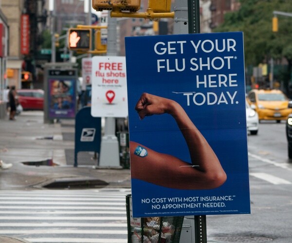 flu shot ad on a street with a woman flexing her arm muscles