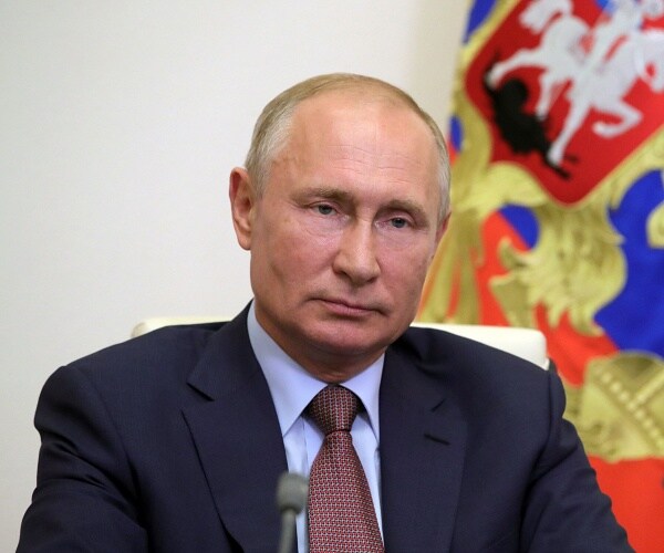 vladimir putin sits at table