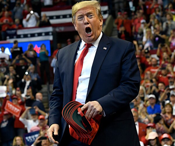 president donald trump exults as he tosses red maga hats to a large rally crowd in florida