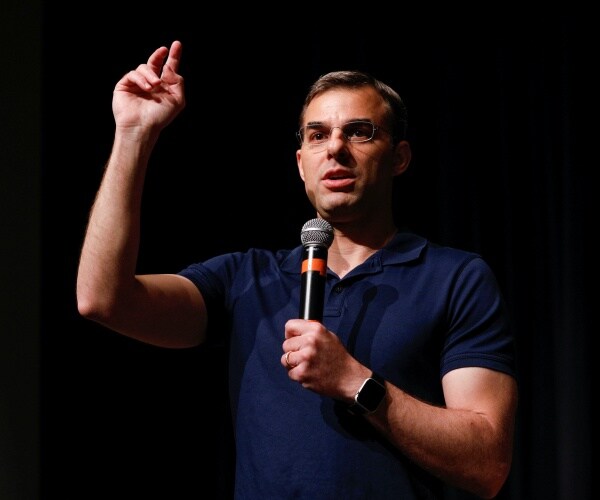 amash in a blue polo shirt speaking into a mic