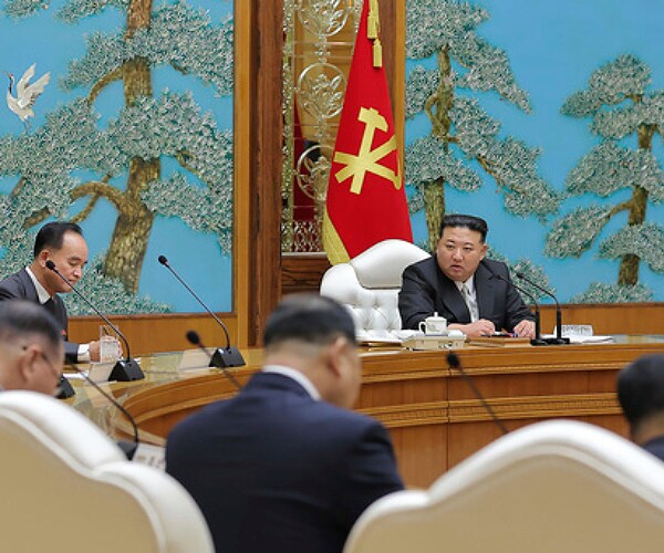kim jong un at a large table leading a meeting