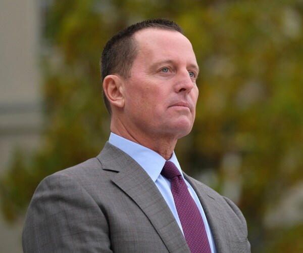 grenell in a light gray suit and purple tie standing outside