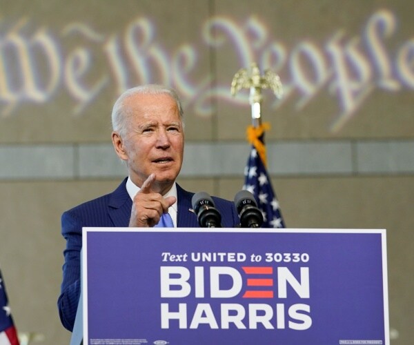 biden speaking at a podium with "we the people" projected behind him