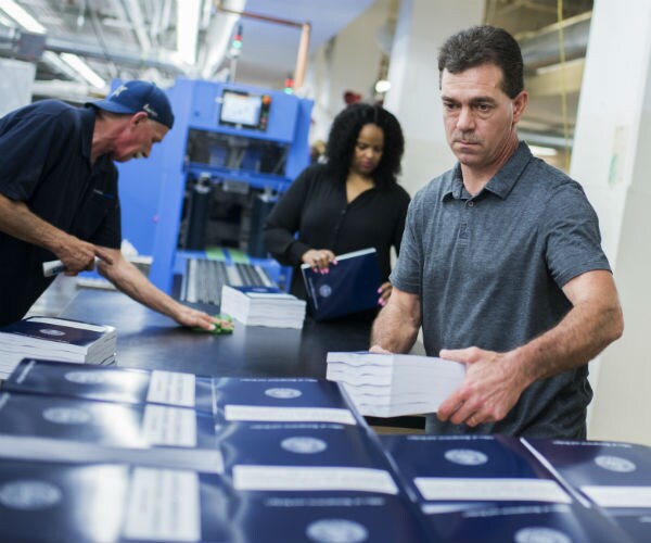 a man stacks copies of the budget at the government publishing office's plant