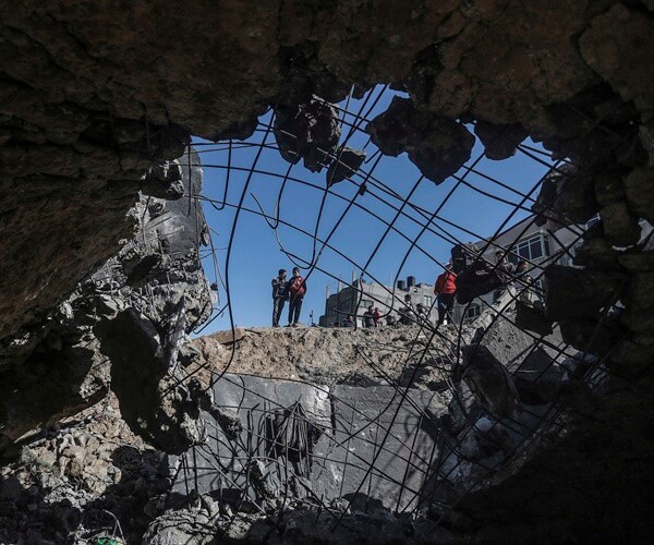 men in gaza inspect a hole from airstrikes