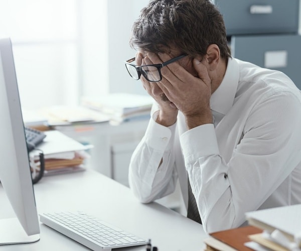 man at desk at work rubbing eyes, stressed