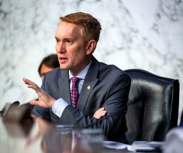 lankford in a dark gray suit and purple tie sitting at a table