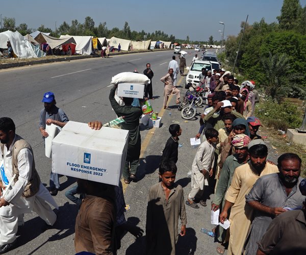 Displaced families receive food and take refuge on a roadside in Pakistan