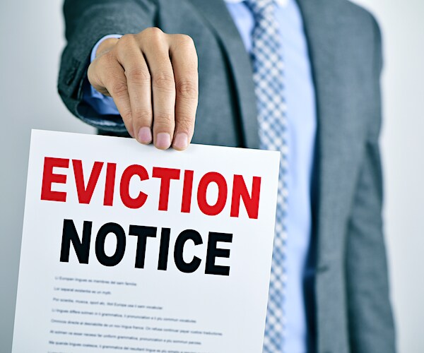 a man holds up a red lettered eviction notice on a white legal paper