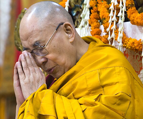 the dalai lama bends his head over and prays