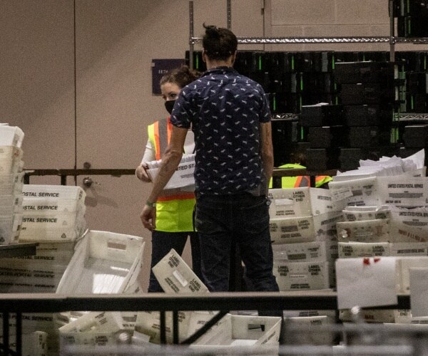 election workers stand amongst ballot bins