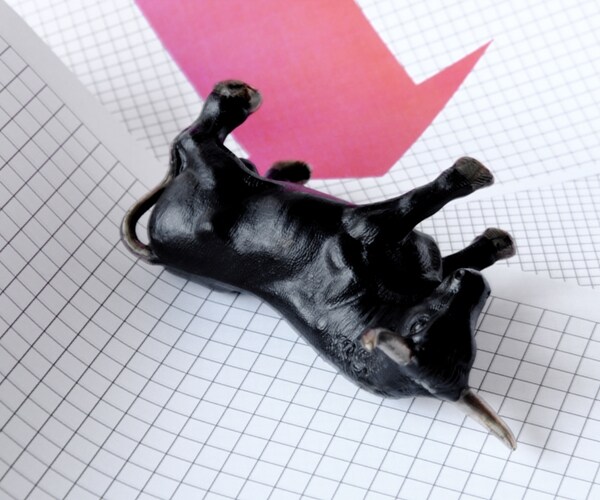 A black bull with a red arrow pointing down on sheets of graph paper 