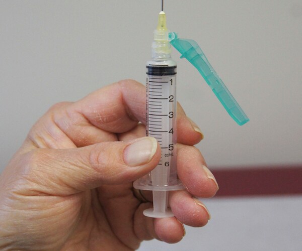 a man holds a syringe up in the air