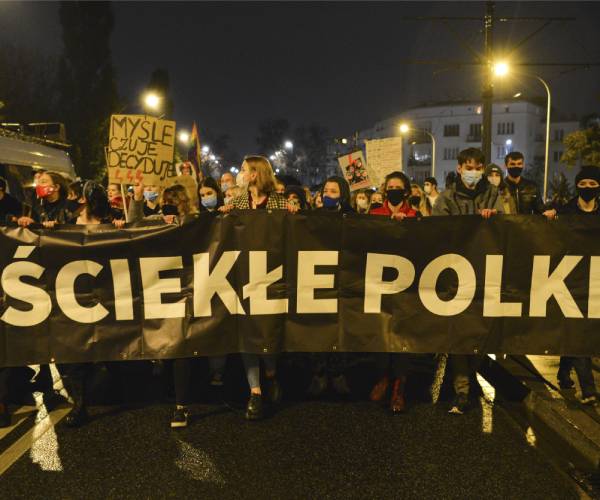 protesters carrying signs and a large banner