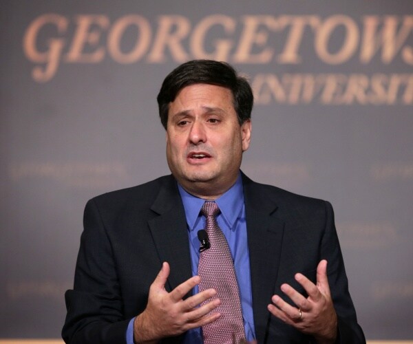 klain in a black suit blue shirt and purple tie at a georgetown event