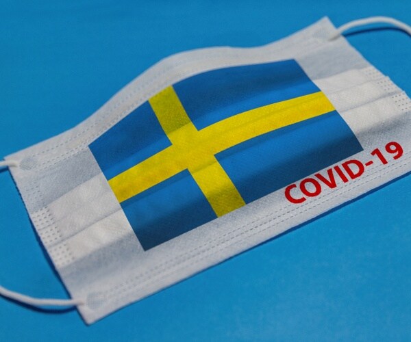 medical face mask with flag of sweden and covid-19 text on blue background