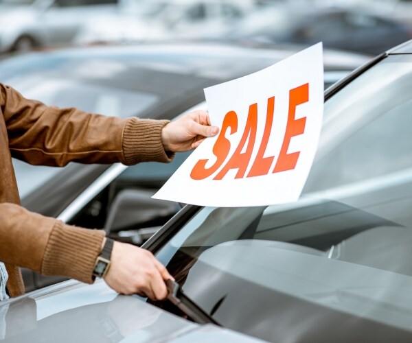 a man places a sale sign on a car