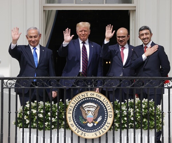 the signers of the abraham accords stand in on a balcony with the presidential seal 
