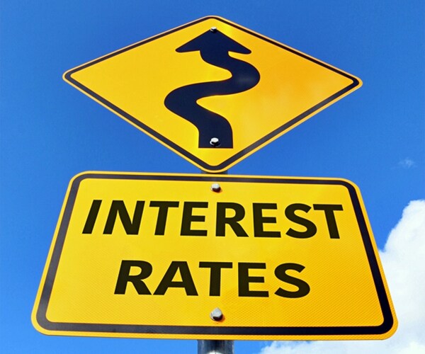yellow and black interest rates rising road sign in a blue sky.

