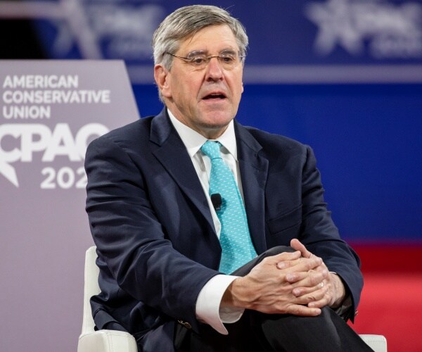 stephen moore sits with legs crossed onstage