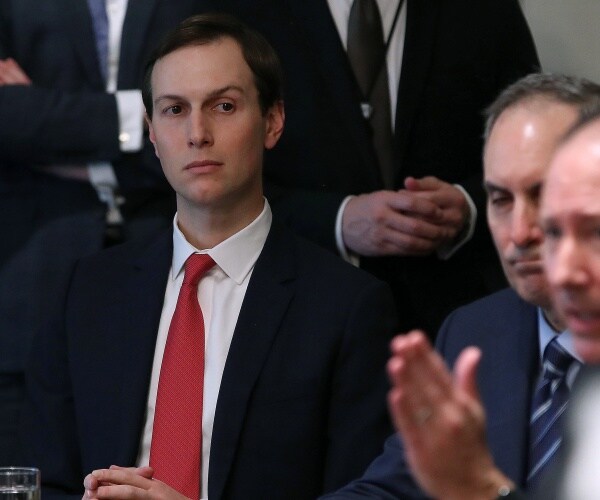 jared kushner wearing a suit with a red tie slightly raising his eyebrow 