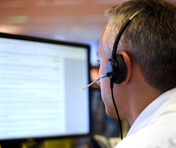 a man on a headset sits before a computer screen at work