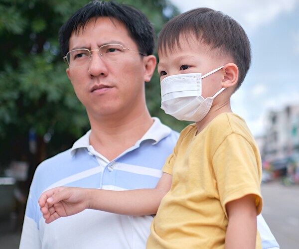 a man and with his son protecting himself with a face mask
