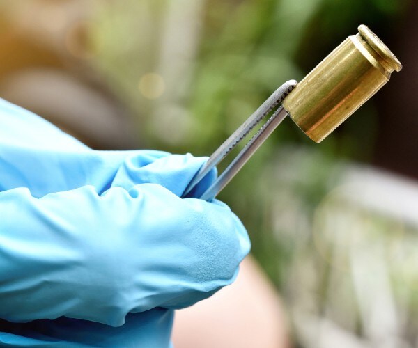 an investigator looks at a bullet casing