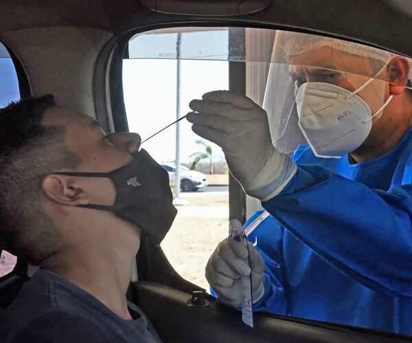 a health worker swabs a driver for COVID-19 testing