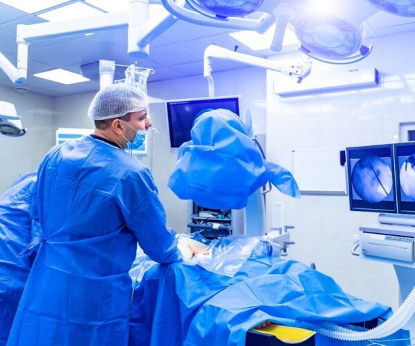 surgeons performing spinal fusion surgery in operating room
