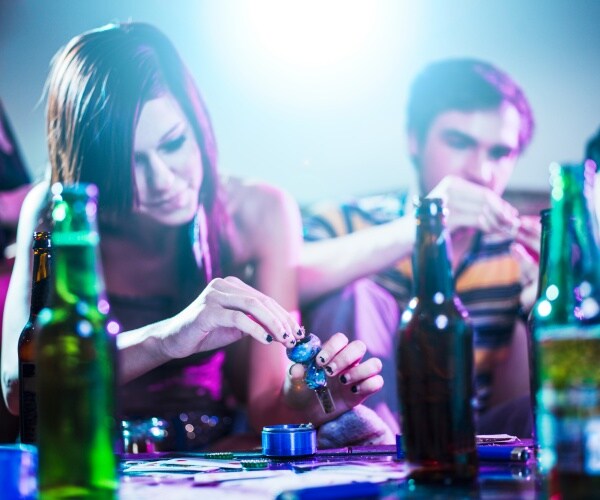 teenage girl and boy drinking, doing drugs, at a party