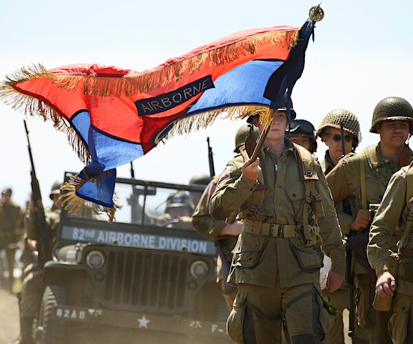 army airborne soldiers carry a flag as they march