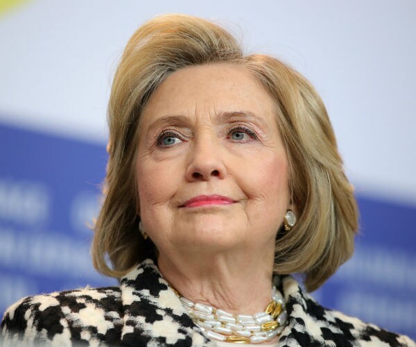 hillary clinton is seen in a black and white print dress with a bold and white necklace