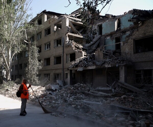 communal workers sweep debris of a destroyed building