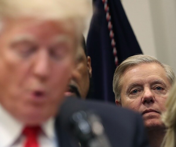 lindsey graham stares off in the background as donald trump reads a speech on the prison reform bill.