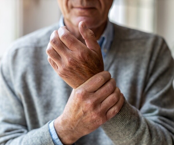 man rubbing his hands because they hurt from arthritis
