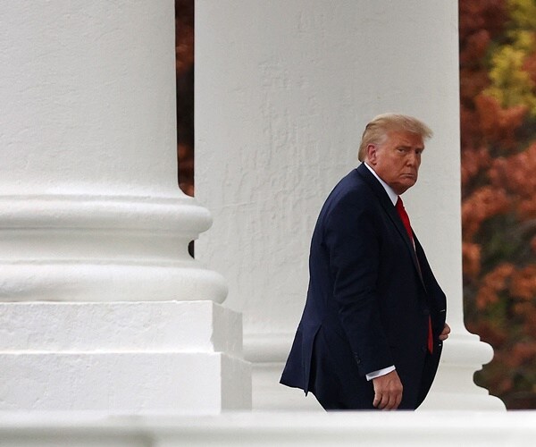 president trump walks through a outdoor walkway at the white house