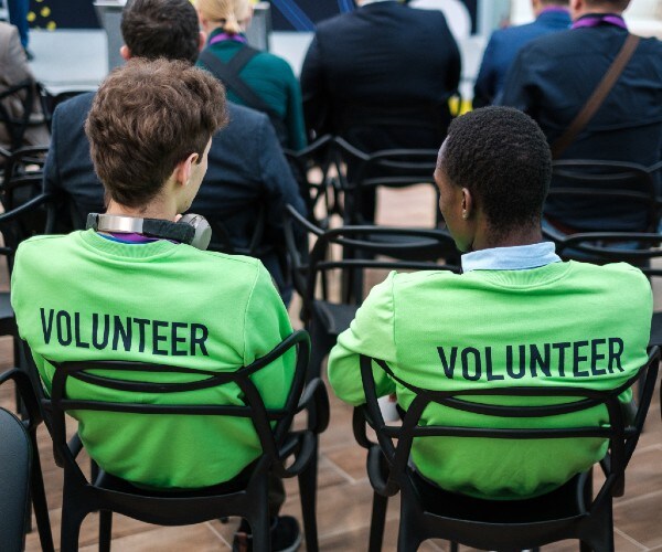 two people seated in chairs with volunteer written on the backs of their tee shirts
