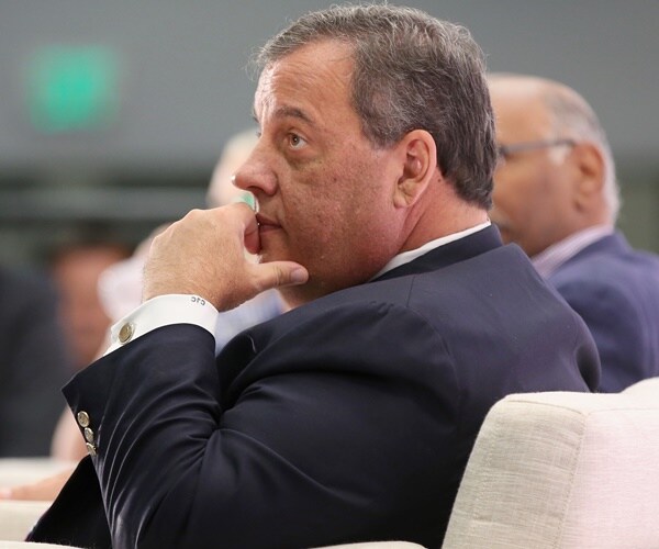 chris christie listens to a speaker