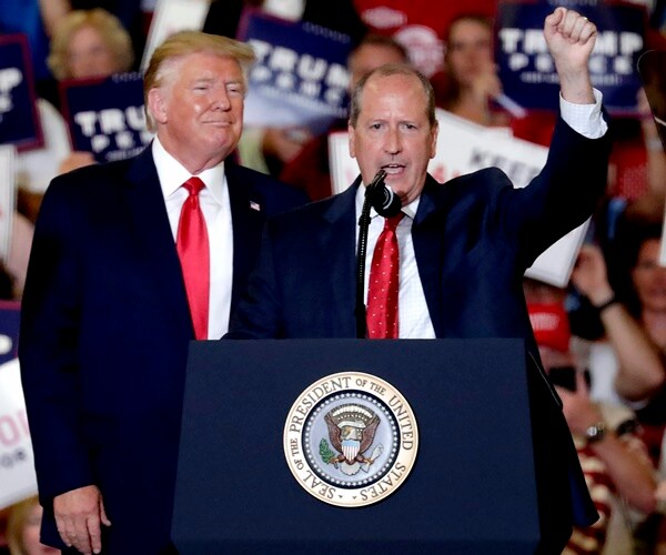 dan bishop raisers his hand on podium next to president rump