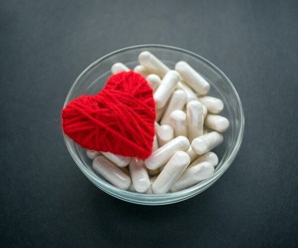 a heart on a bowl of anti-clotting drug capsules