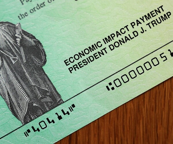 a corner of a stimulus check to an american citizen during the coronavirus crisis.