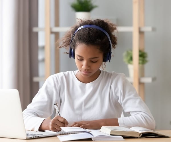 teen doing homework with headphones
